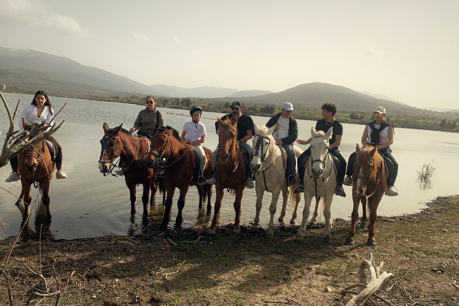 Riders on horseback by a mountain lake near Segovia